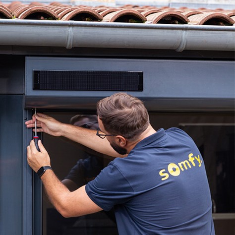 Installateur Somfy devant volet roulant solaire