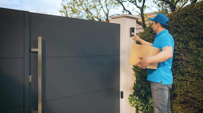 delivery man in front of gate ringing somfy door phone bell